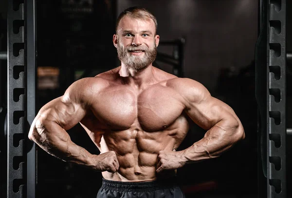 Schöner fitter kaukasischer muskulöser Mann, der seine Muskeln im Fitnessstudio spielen lässt — Stockfoto