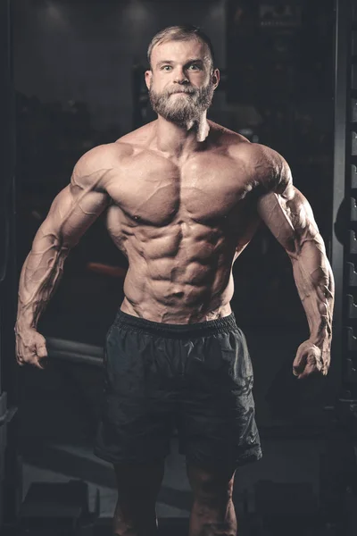 Snygg passform kaukasiska muskulös man flexar sina muskler i gymmet — Stockfoto