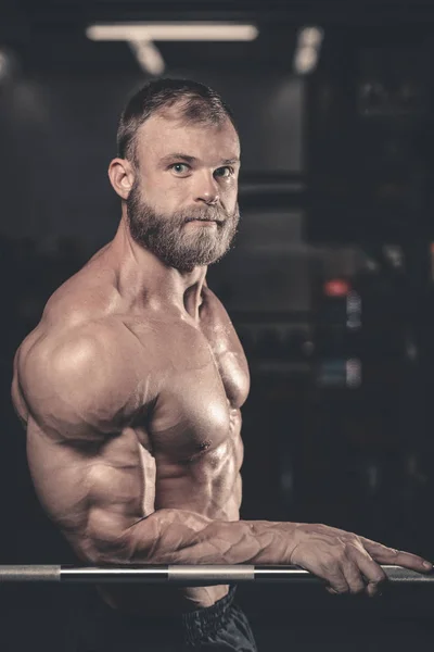 Handsome fit caucasian muscular man flexing his muscles in gym — Stock Photo, Image