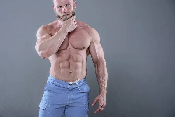 Brutal musculoso hombre en estudio en gris fondo fitness modelo — Foto de Stock