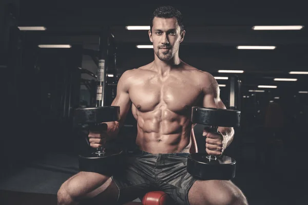 Caucasian sexy fitness male model execute exercise with dumbbell