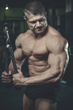 Yakışıklı model genç adam eğitim kollarında spor salonu