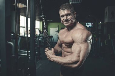 Yakışıklı model genç adam eğitim kollarında spor salonu