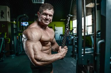 Yakışıklı model genç adam eğitim kollarında spor salonu