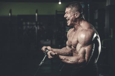 Yakışıklı model genç adam eğitim kollarında spor salonu