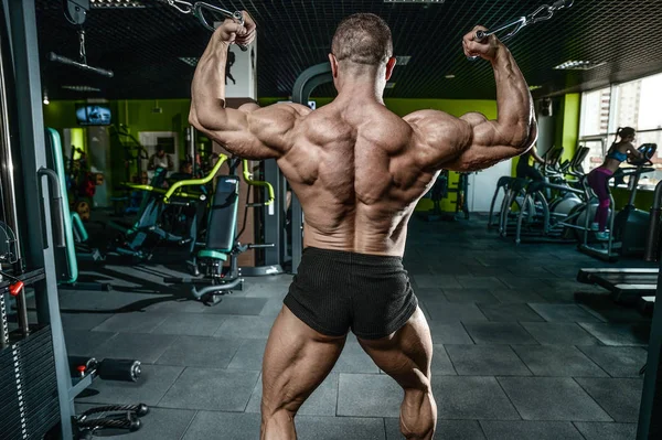 Yakışıklı model genç adam eğitim kollarında spor salonu