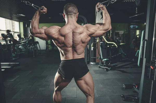 Yakışıklı model genç adam eğitim kollarında spor salonu