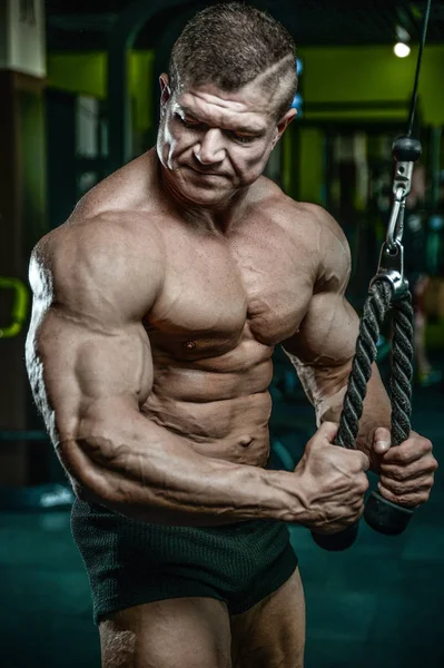 Bello modello giovane uomo formazione braccia in palestra — Foto Stock