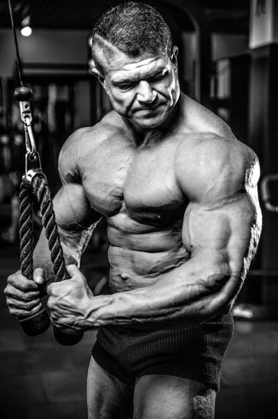 Yakışıklı model genç adam eğitim kollarında spor salonu