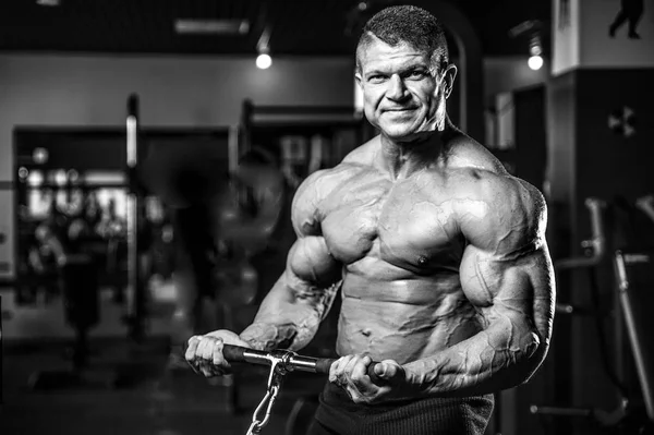 Bello modello giovane uomo formazione braccia in palestra — Foto Stock