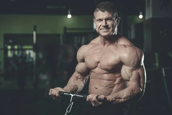Gut aussehend modell junger mann training arms im fitnessstudio — Stockfoto