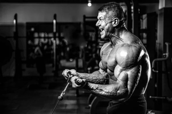 Guapo modelo joven entrenamiento brazos en el gimnasio —  Fotos de Stock