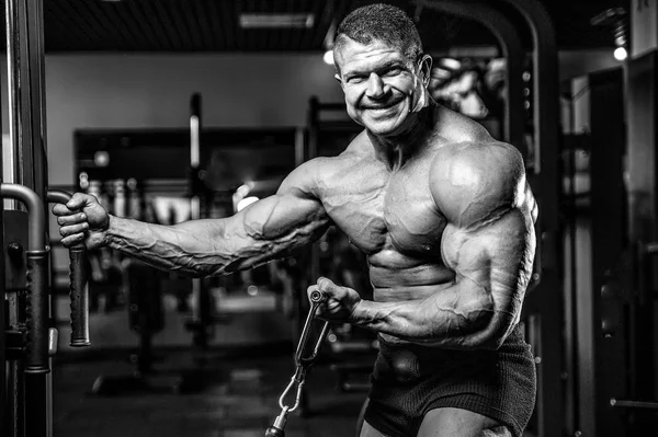 Guapo modelo joven entrenamiento brazos en el gimnasio —  Fotos de Stock