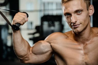 Yakışıklı model genç adam eğitim kollarında spor salonu