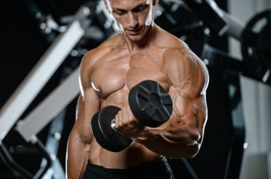 Yakışıklı model genç adam eğitim kollarında spor salonu