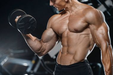 Yakışıklı model genç adam eğitim kollarında spor salonu