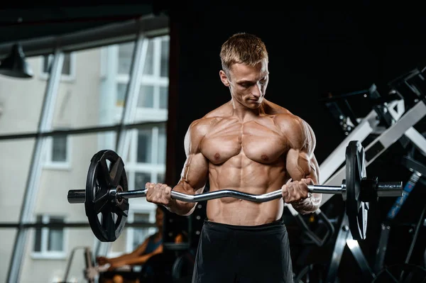 Bello modello giovane uomo formazione braccia in palestra — Foto Stock