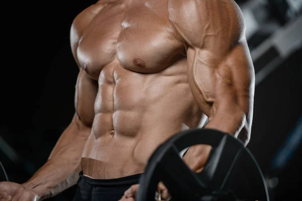 Guapo modelo joven entrenamiento brazos en el gimnasio — Foto de Stock