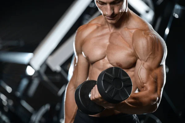 Guapo modelo joven entrenamiento brazos en el gimnasio —  Fotos de Stock