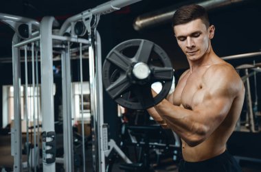 Yakışıklı model genç adam eğitim kollarında spor salonu