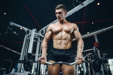 Yakışıklı model genç adam eğitim kollarında spor salonu