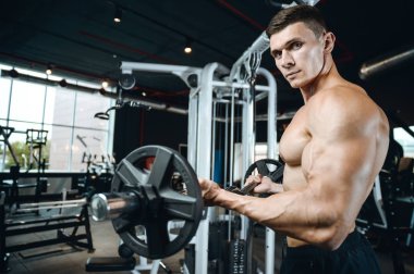 Yakışıklı model genç adam eğitim kollarında spor salonu