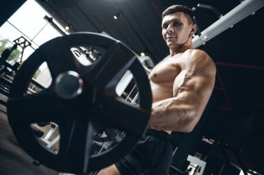 Yakışıklı model genç adam eğitim kollarında spor salonu