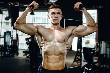 Yakışıklı model genç adam eğitim kollarında spor salonu