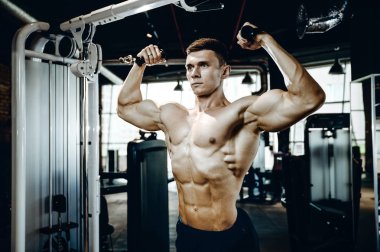 Yakışıklı model genç adam eğitim kollarında spor salonu