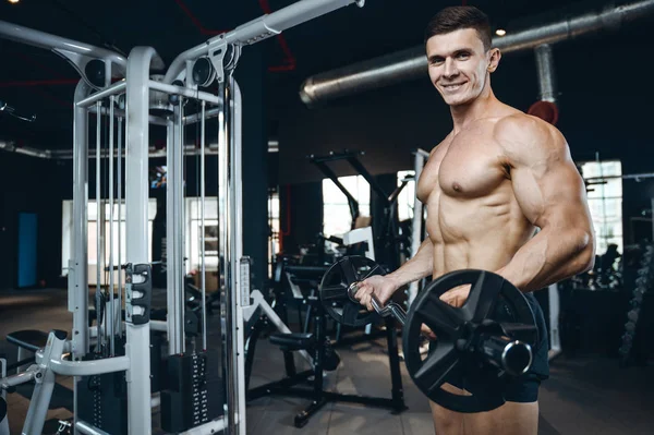 Yakışıklı model genç adam eğitim kollarında spor salonu