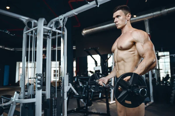 Yakışıklı model genç adam eğitim kollarında spor salonu