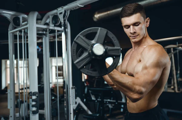 Yakışıklı model genç adam eğitim kollarında spor salonu