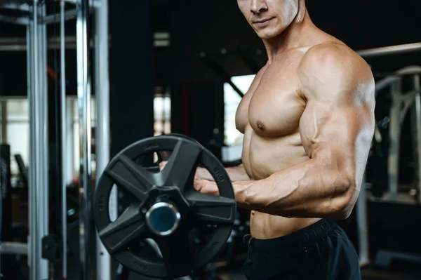 Guapo modelo joven entrenamiento brazos en el gimnasio —  Fotos de Stock