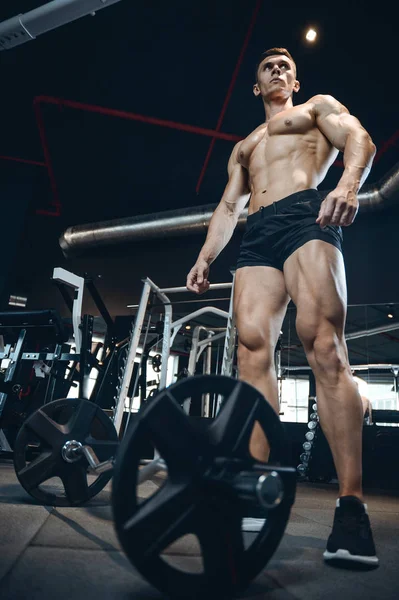 Guapo modelo joven entrenamiento piernas en el gimnasio — Foto de Stock
