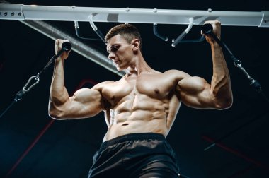 Yakışıklı model genç adam eğitim kollarında spor salonu