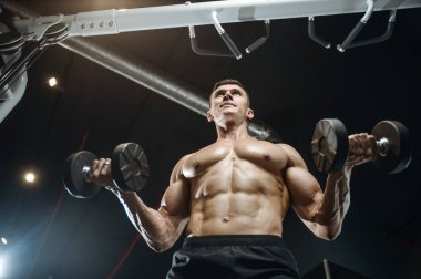 Yakışıklı model genç adam eğitim kollarında spor salonu