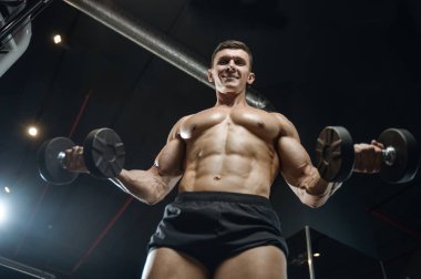 Yakışıklı model genç adam eğitim kollarında spor salonu