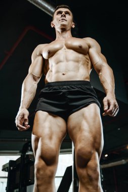 Yakışıklı model genç adam eğitim bacaklar içinde jimnastik salonu