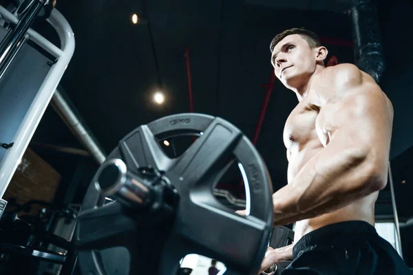 Handsome model young man training arms in gym