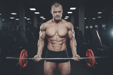 Yakışıklı model genç adam eğitim kollarında spor salonu