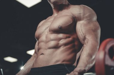 Yakışıklı model genç adam eğitim kollarında spor salonu