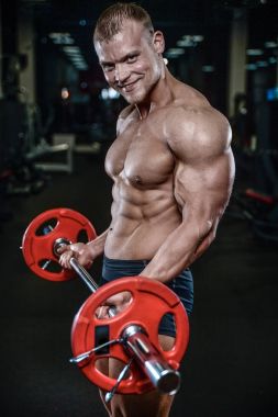 Yakışıklı model genç adam eğitim kollarında spor salonu