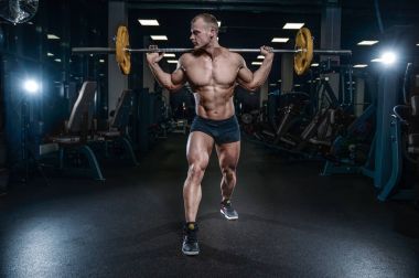 Yakışıklı model genç adam eğitim bacaklar içinde jimnastik salonu