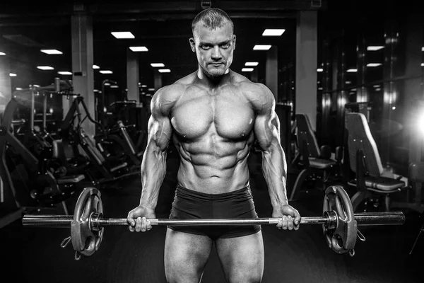 Guapo modelo joven entrenamiento brazos en el gimnasio — Foto de Stock