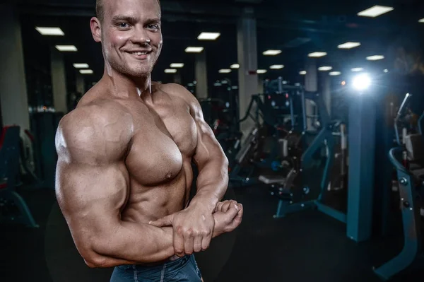 Guapo modelo joven entrenamiento brazos en el gimnasio —  Fotos de Stock