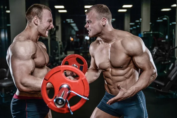 Guapo modelo joven entrenamiento brazos en el gimnasio —  Fotos de Stock