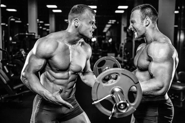 Guapo modelo joven entrenamiento brazos en el gimnasio —  Fotos de Stock