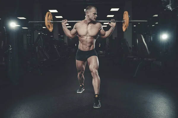 Bonito modelo jovem treinando pernas no ginásio — Fotografia de Stock