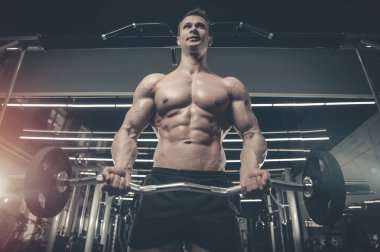 Yakışıklı model genç adam eğitim kollarında spor salonu