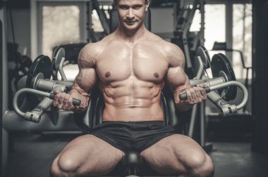 Yakışıklı model genç adam eğitim kollarında spor salonu